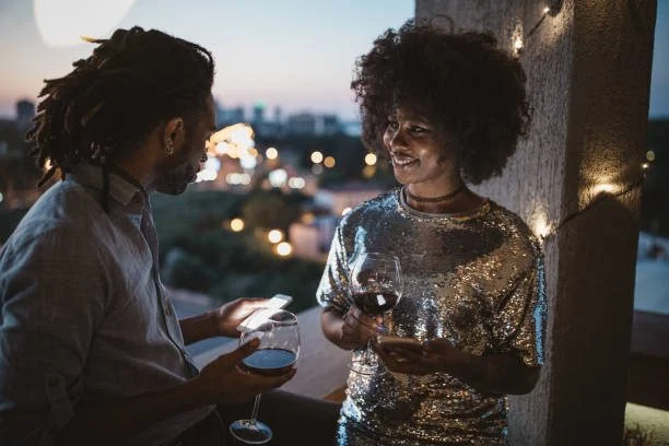 A couple sharing wine on a balcony at dusk